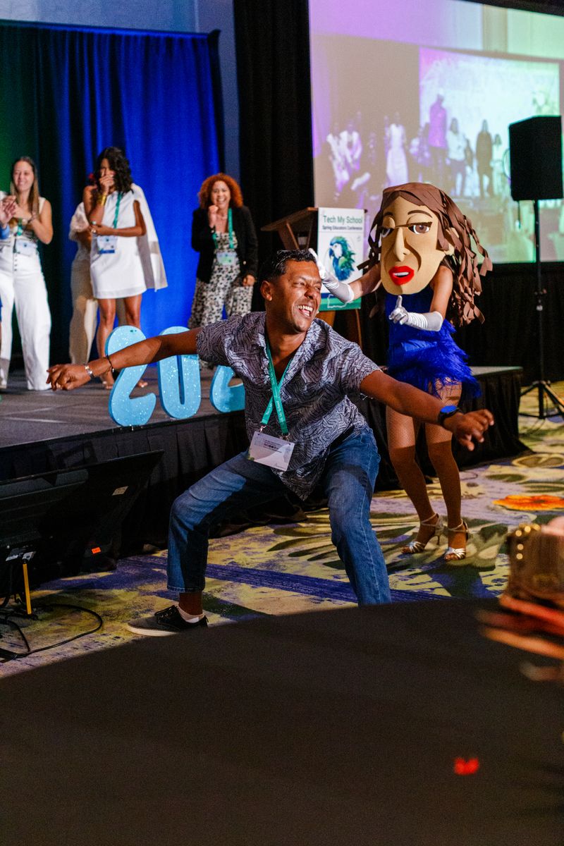 An educator dancing with a cabezudo during the closing celebration